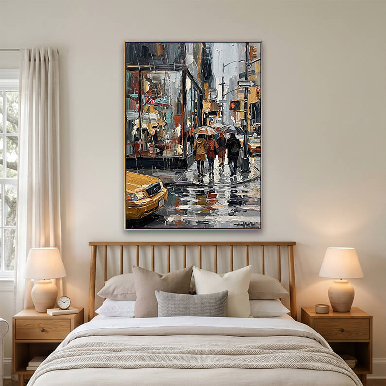 A minimalist bedroom mockup featuring a gold-framed rainy city street painting mounted above a light oak wood spindle bed. The bed is styled with cream and beige linens, flanked by matching wooden nightstands with round ceramic table lamps.
