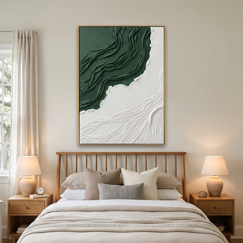 A cozy, bright bedroom featuring the framed green and white textured abstract painting hung above a light wooden spindle headboard. The bed is styled with neutral beige and off-white linens, flanked by matching wooden bedside tables with warm white ceramic lamps.