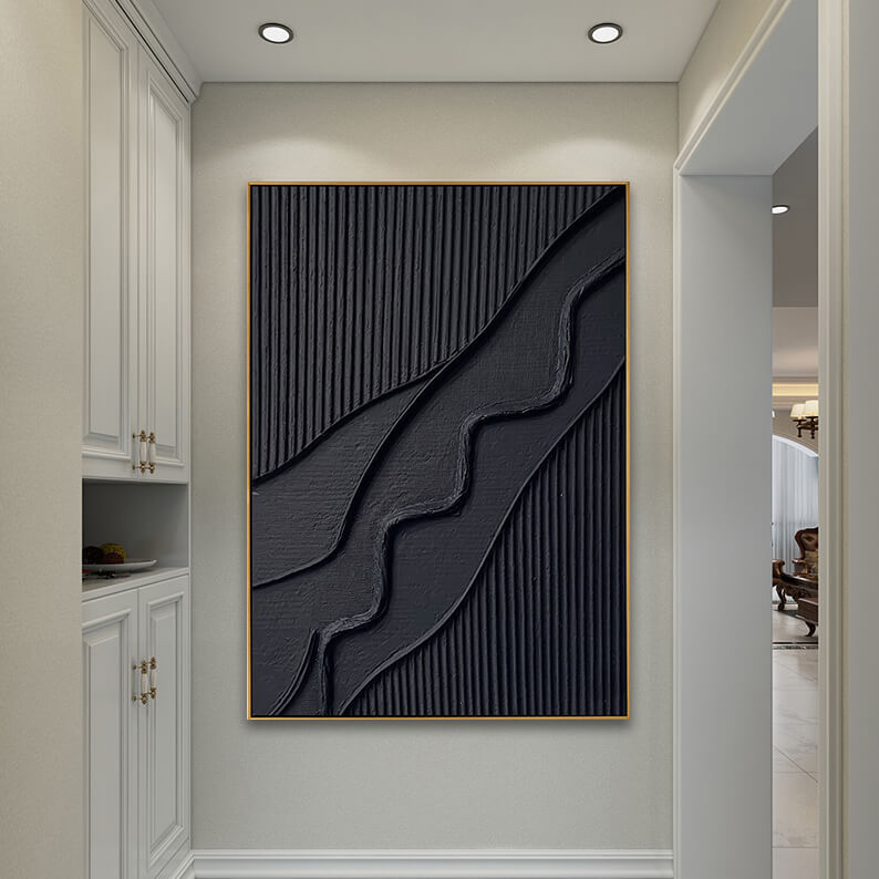 A perspective view down a modern, elegant residential hallway. The black textured 3D painting is centrally mounted on the main cream-colored wall, brightly illuminated by two warm recessed spotlights from the ceiling. On the left are sleek, built-in floor-to-ceiling white cabinets with gold T-bar handles. The hallway floor is tiled in a light, polished stone, leading toward a brightly lit living area on the right.