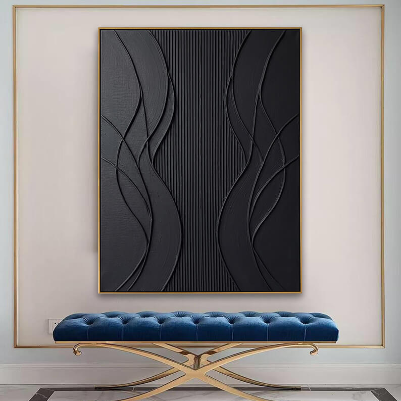 The large gold-framed black textured canvas artwork is centered on a light cream wall accented by a thin gold-metal geometric wall trim. Directly beneath the painting is an elegant, deep-blue velvet tufted bench with curved, polished gold legs. The polished marble flooring in the foreground reflects light, presenting a luxurious, high-end entryway or lobby design.
