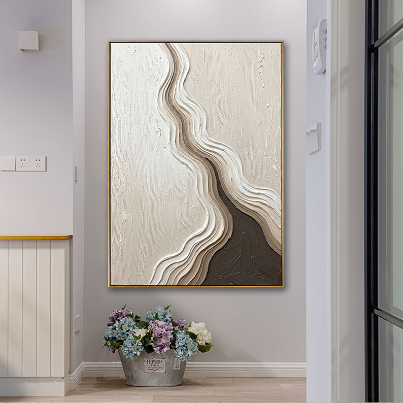 Vertical textured canvas wall art featuring flowing brown and cream lines in a bright modern hallway next to a bucket of hydrangeas.
