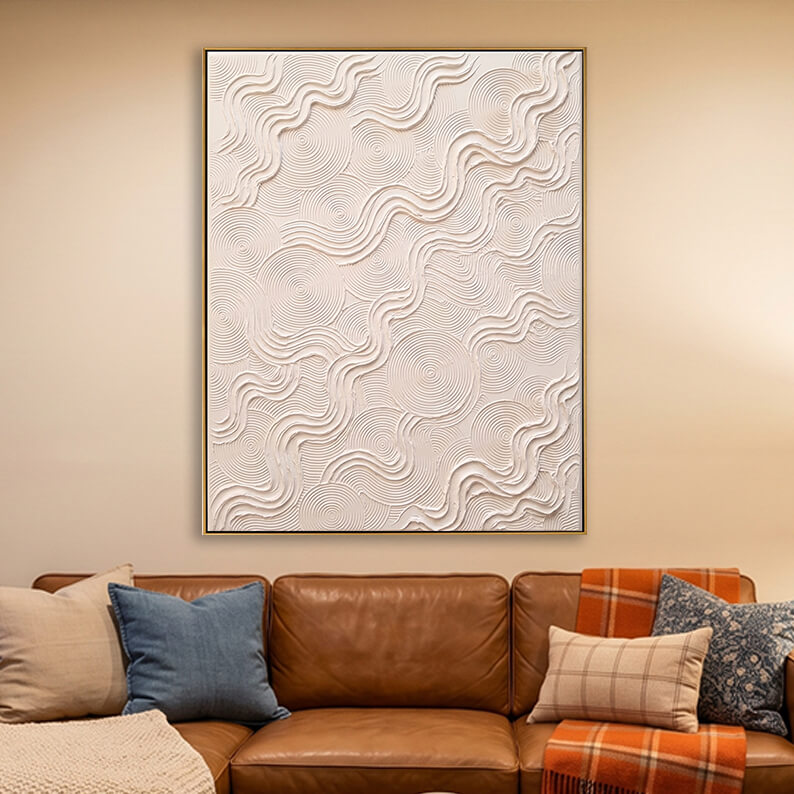 Modern impasto white canvas art hanging above a rich brown leather sofa in a warm, contemporary living room.