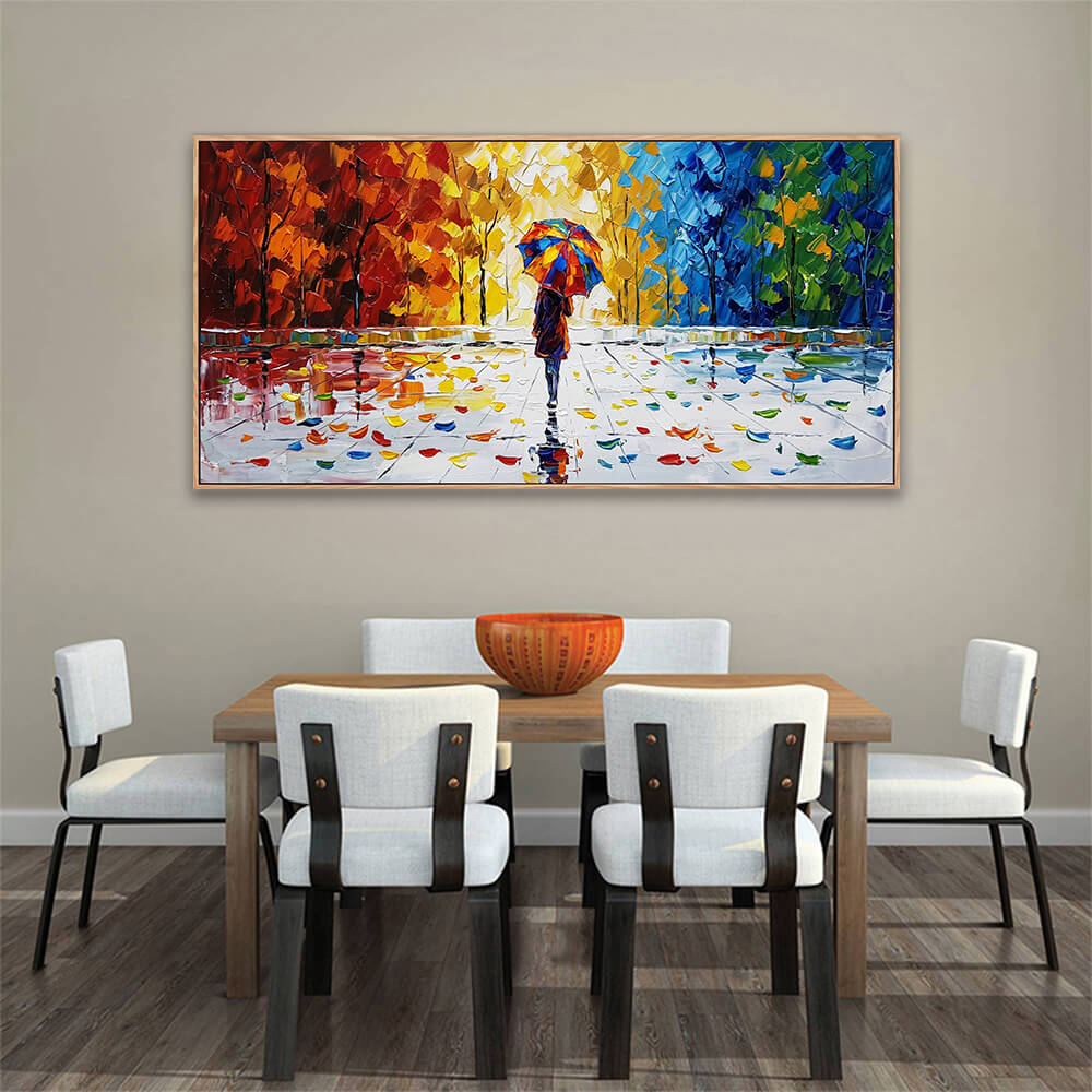 Vibrant horizontal autumn landscape art with a solitary figure under a colorful umbrella displayed over a light wood dining set.