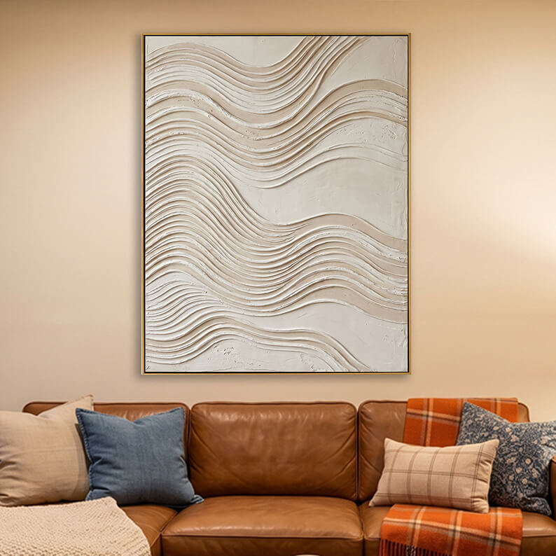 Beige 3D textured layered wave painting hanging above a brown leather sofa in a warm living room.