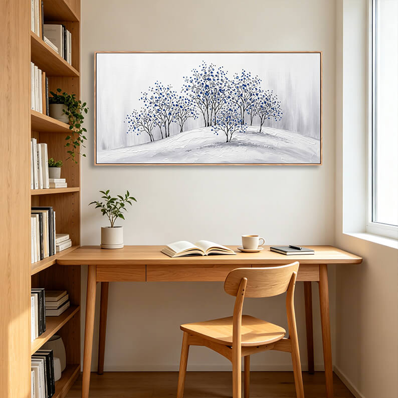 Elegant textured blue and grey winter forest painting displayed in a modern home office above a wooden desk.