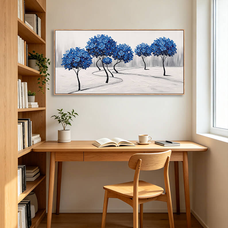 Elegant textured cobalt blue tree landscape painting displayed on a wall in a cozy home office above a wooden writing desk.