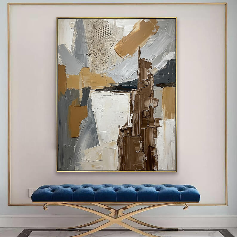 Modern textured brown and grey canvas art displayed above a tufted blue velvet bench in an elegant entryway.