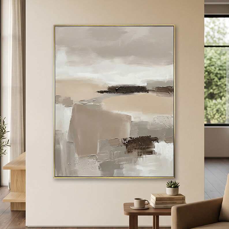 Minimalist beige and grey 3D textured canvas art displayed on a neutral wall above a small wooden table with books.
