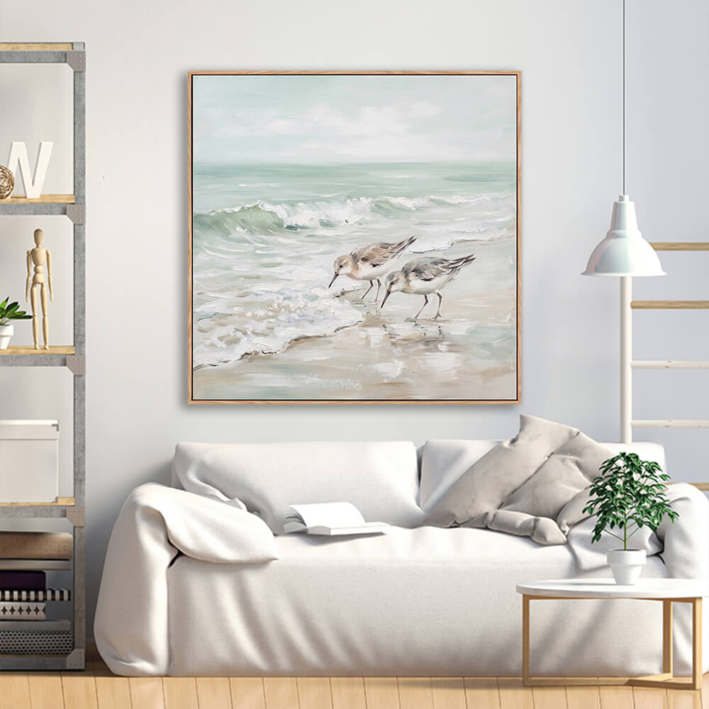 Muted sandpiper shorebird seascape painting above cream linen sofa in minimalist living room