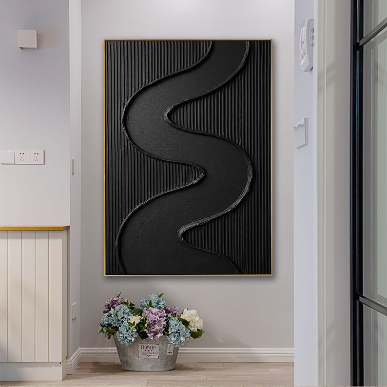 Modern black abstract art piece with heavy texture positioned above a decorative bucket of flowers.