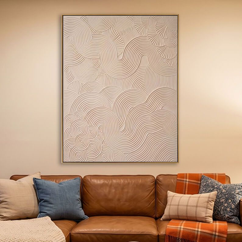 Textured beige swirl abstract artwork displayed in a warm living room over a leather couch.
