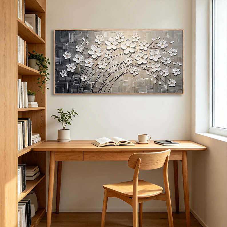 Elegant textured white floral landscape painting displayed on a wall in a cozy home office above a wooden writing desk.