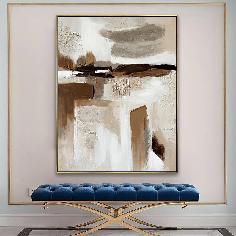 Modern textured brown and beige canvas art displayed above a tufted blue velvet bench in an elegant entryway.