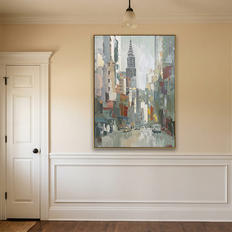 A mockup of a large, gold-framed impressionist city painting mounted on a clean, light grey accent wall. The room is exceptionally bright and spacious, featuring light wood floors and large symmetric bay windows on both sides that overlook lush green trees.