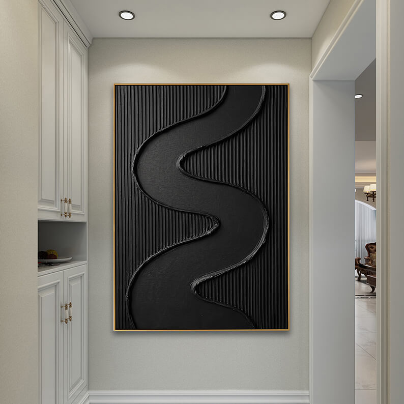 The black textured 3D artwork is centered on an off-white wall at the end of a clean hallway, illuminated by warm, recessed ceiling spotlights. To the left is built-in white classical cabinetry with gold handles, and an open doorway on the right leads to a glimpse of a brightly lit living room.