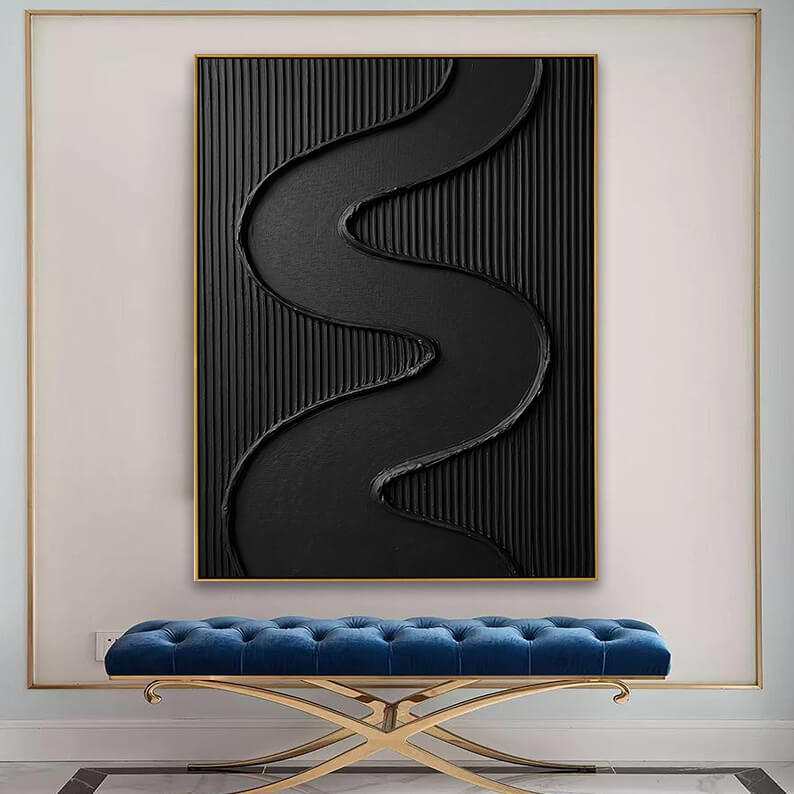 The large, textured black painting is displayed on a white wall framed by a thin gold metal trim panel. Positioned below the artwork is a luxurious, tufted royal blue velvet bench with cross-legged gold chrome supports, set against a polished grey and white marble floor.