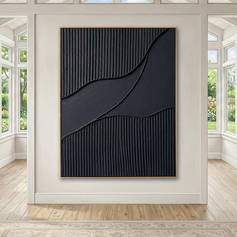 A bright, spacious, and airy interior hallway or sunroom. The gold-framed black textured artwork is hung on a light gray-white wall. The room features high ceilings, light-toned hardwood flooring, and large multi-pane windows on both sides that offer a view of a lush, sunny green garden outside.