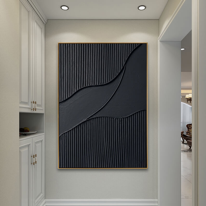 A clean and luxurious modern hallway. The black textured art piece hangs prominently on the end wall, illuminated by recessed warm spotlights from the ceiling. To the left is a tall, built-in white wardrobe/cabinet with sleek gold pull handles. The floor is light, reflecting the bright overhead lighting, and an adjacent entryway leads into a beautifully lit living area.