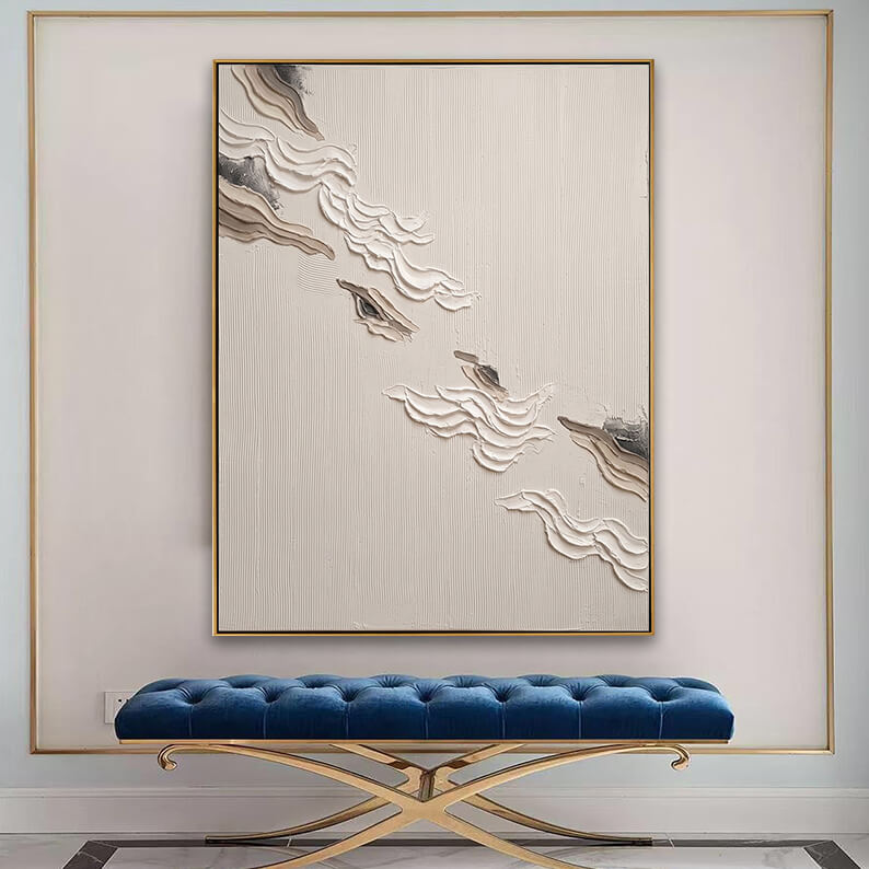 Large framed abstract wall art in cream and charcoal displayed over a chic blue velvet bench in an elegant home foyer.