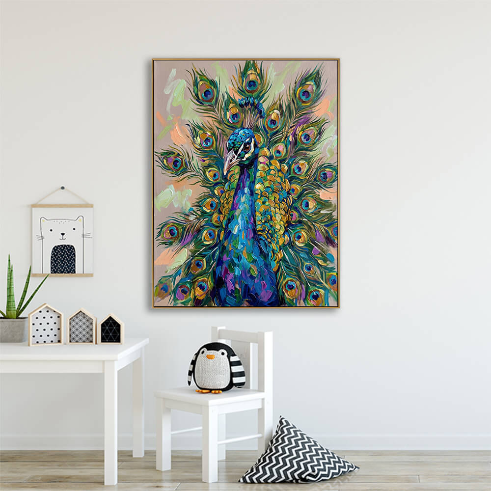 The peacock oil painting is hung low on a bright white wall in a cozy, minimalist child's bedroom or playroom. Below the painting is a small white wooden chair featuring a cute black-and-white plush penguin toy. To the left is a small white wooden play table decorated with a tiny potted succulent and miniature wooden houses. A framed minimalist cartoon cat illustration hangs on the wall, and a black-and-white zig-zag patterned throw pillow rests on the light oak hardwood floor.
