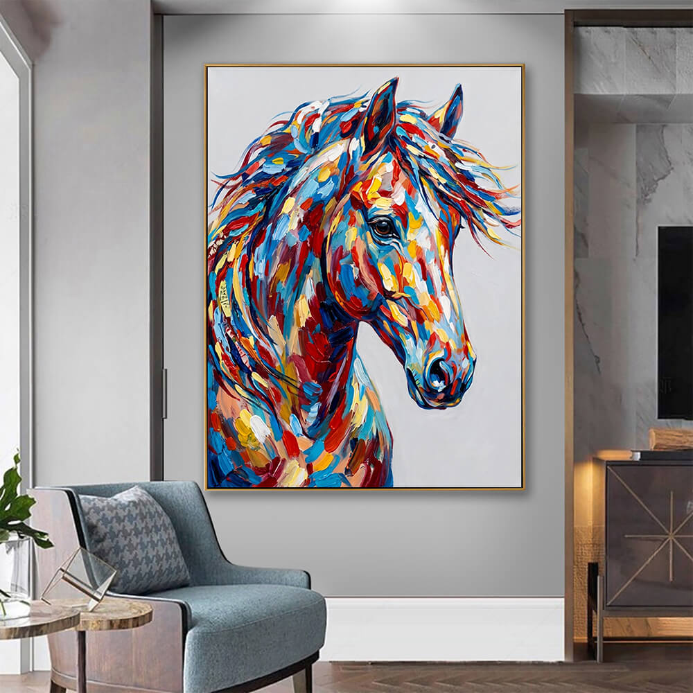 The framed horse painting is displayed in a moody, modern living room mockup. It is mounted on a sleek gray feature wall next to a glass sliding door. In the foreground, a comfortable blue-gray fabric armchair with a patterned cushion sits next to a small wooden side table, highlighting the painting as a focal point.