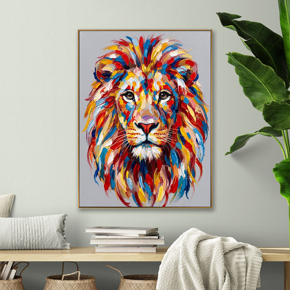 Abstract lion canvas painting hung above a wooden console table with a large green leaf plant in a bright room.