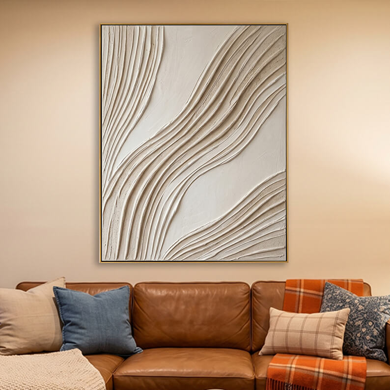 Beige 3D textured wave painting hanging above a brown leather sofa in a warm, modern living room.