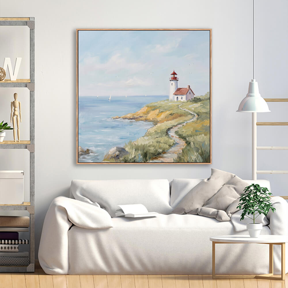 Warm grassy cliff lighthouse seascape painting above cream linen minimalist sofa