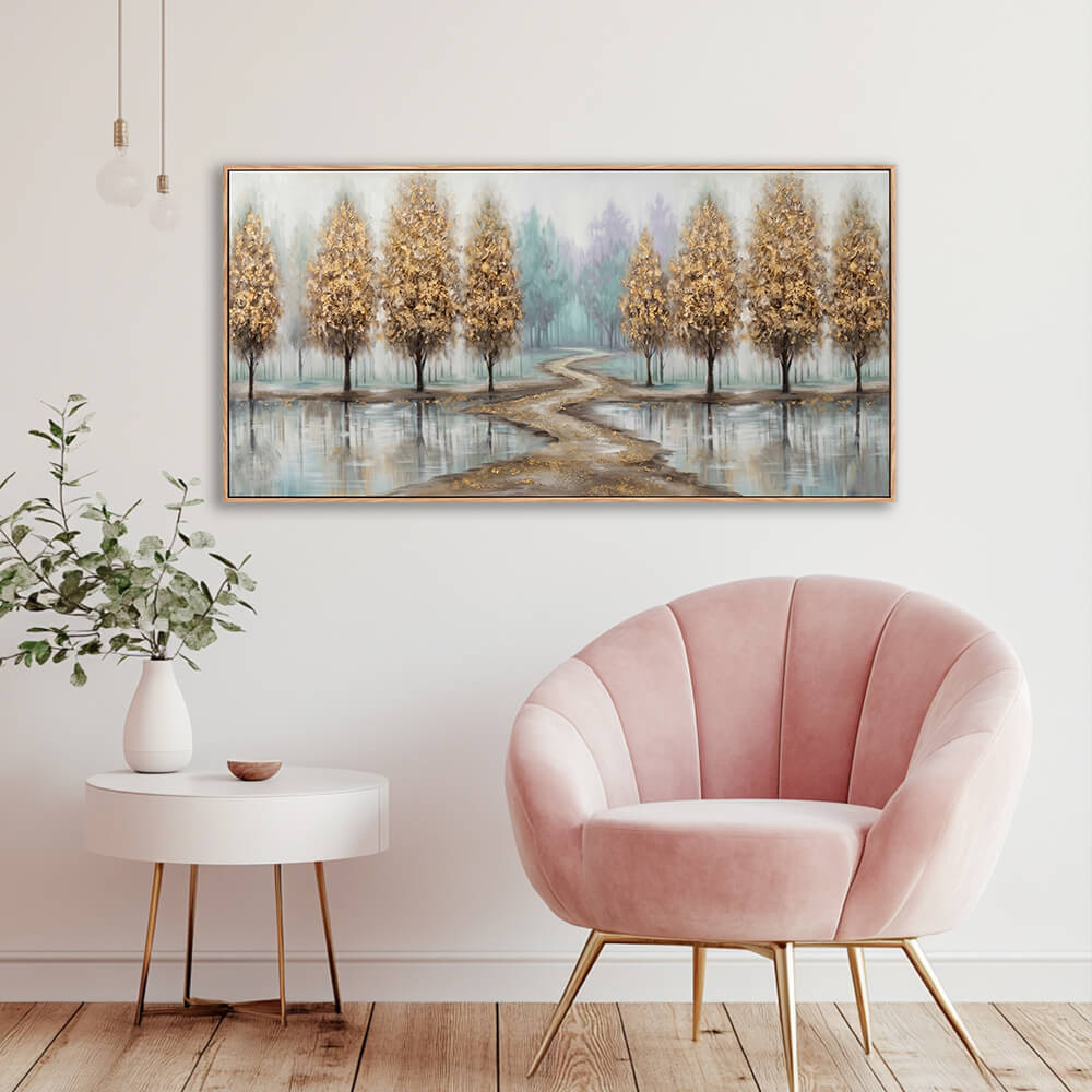 Textured gold and teal misty forest landscape canvas styled in a bright room beside a modern pink velvet chair.