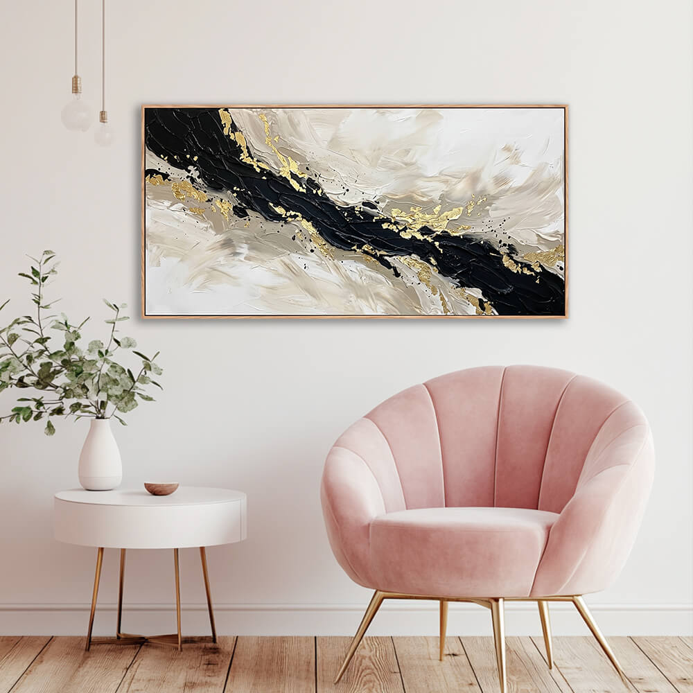 Hand-painted black and gold fluid abstract canvas styled in a chic room next to a pink velvet accent chair.