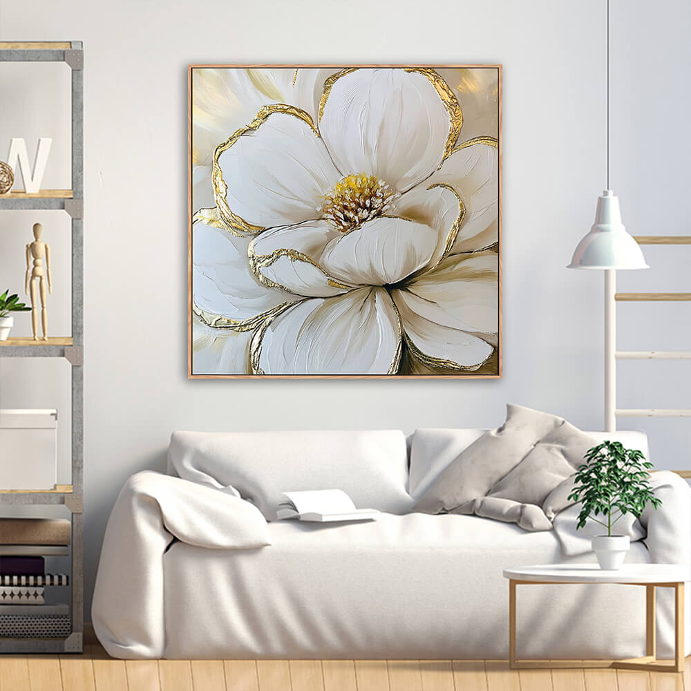 Hand-painted white magnolia gold leaf canvas displayed above soft white linen sofa with industrial metal wood shelf and green foliage plant in bright living room
