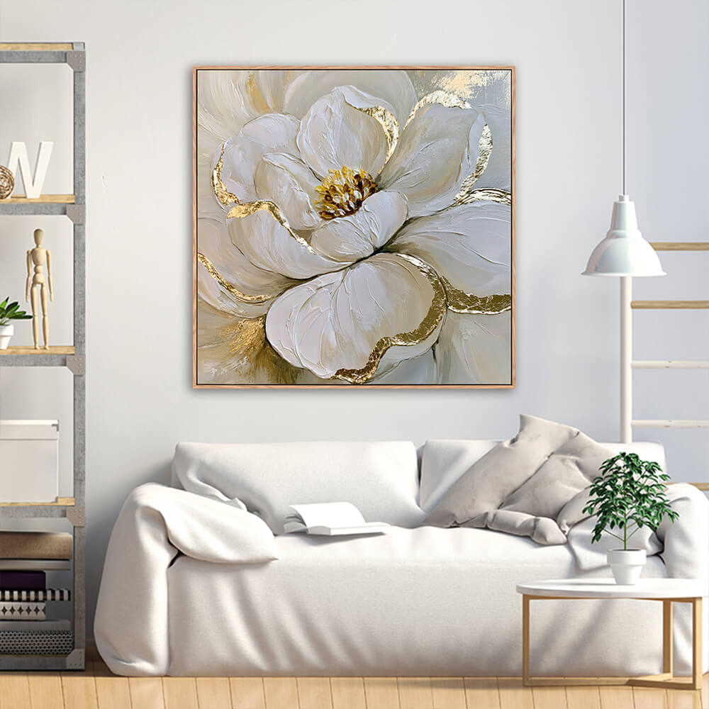 Hand-painted white peony gold leaf canvas displayed above soft white linen sofa with industrial metal wood shelf and green foliage plant in bright living room
