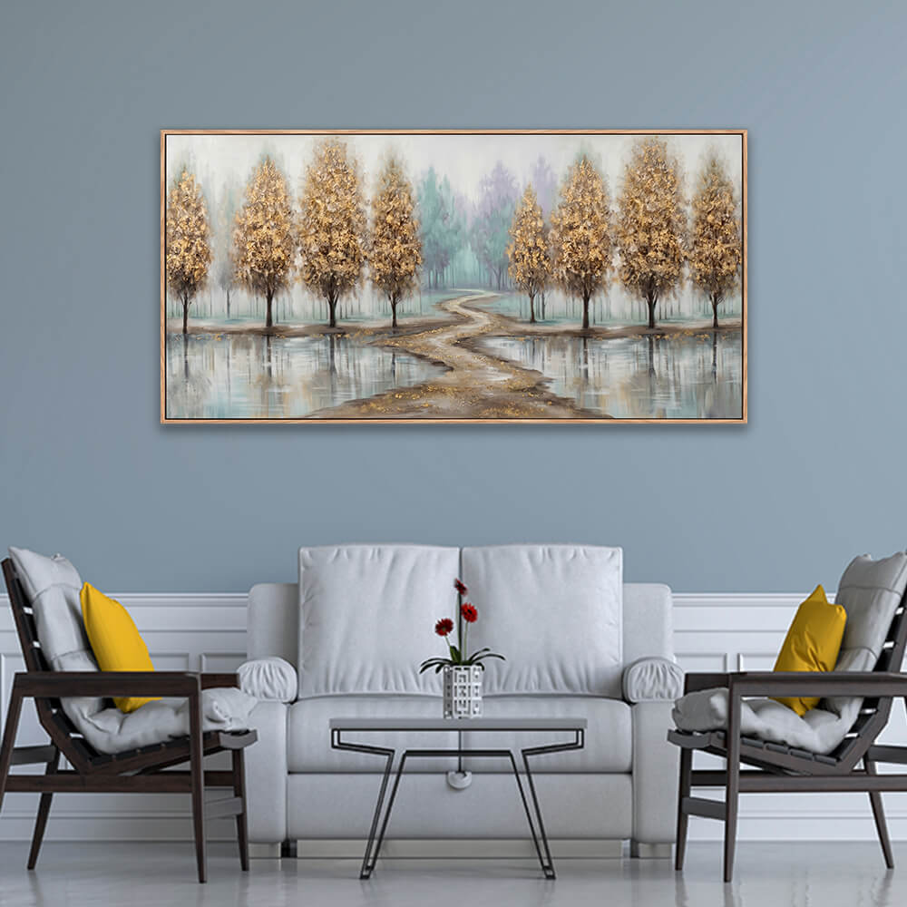 Wide golden tree landscape painting with serene water reflections hanging above a grey sofa in a modern living room.
