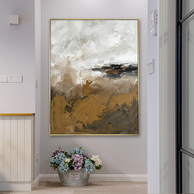 Neutral wabi-sabi style textured abstract canvas art hanging in a bright home corridor next to a bucket of flowers.