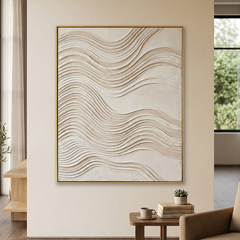 Minimalist beige 3D textured canvas art displayed on a neutral wall above a small wooden table.