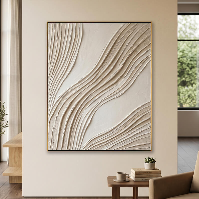 Minimalist beige 3D textured canvas art displayed on a neutral wall above a small table with books.