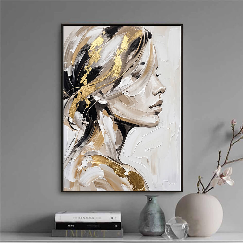 Minimalist interior decor vignette displaying a framed original oil painting of a woman's face next to curated books and a ceramic vase.