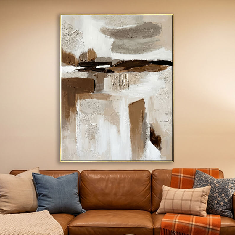 Beige white and dark brown 3D textured abstract painting hanging above a brown leather sofa in a warm modern living room.