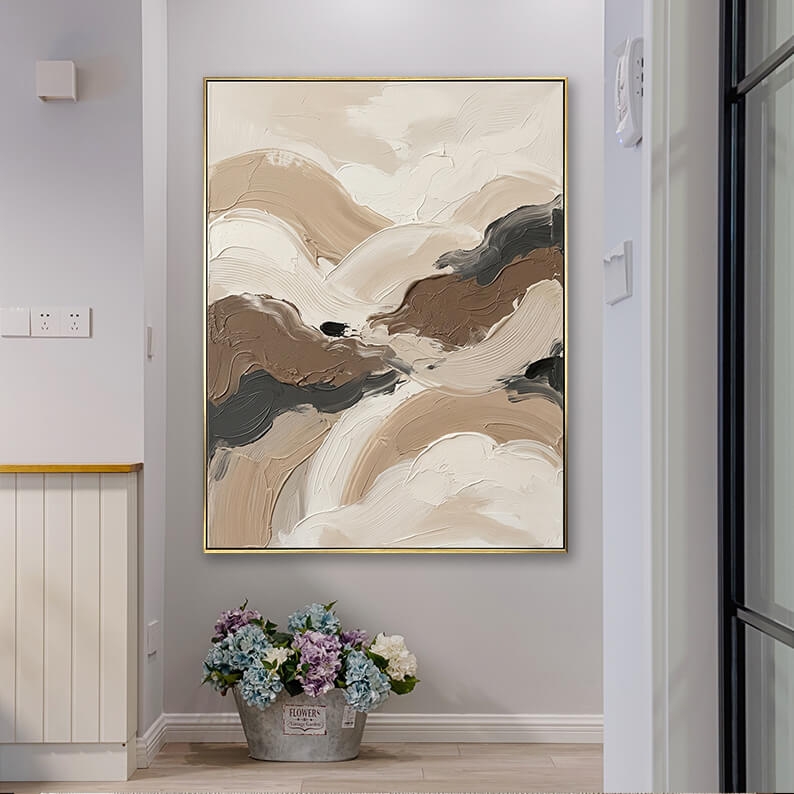 Neutral wabi-sabi style textured abstract canvas art hanging in a bright home corridor next to a bucket of flowers.