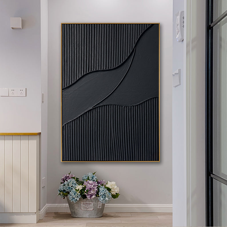 Textured black decorative painting on a neutral wall positioned above a fresh floral arrangement.