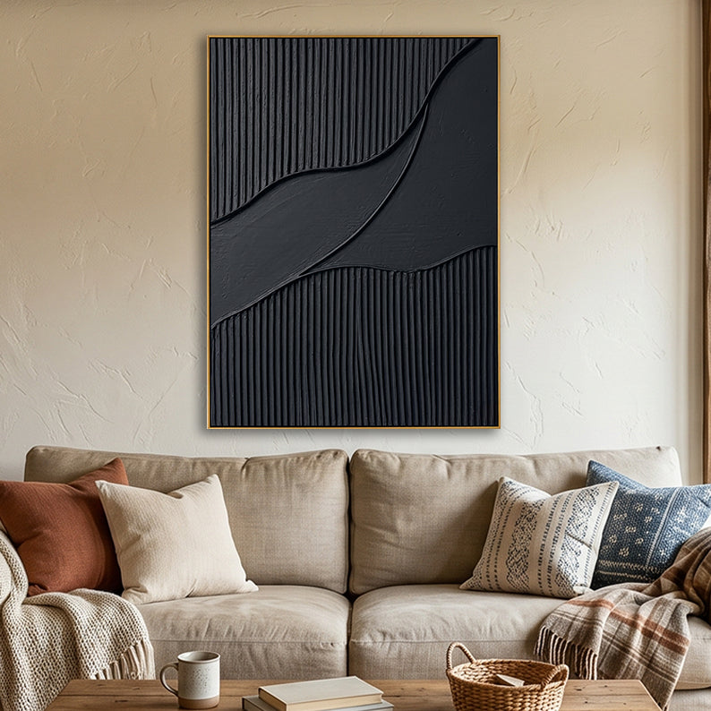 Black plaster-style textured art above a beige sofa with warm earth-toned accent pillows.